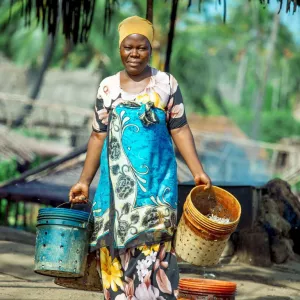 A woman fish processor on Mafia Island, Tanzania, carries boiled small pelagic fish for further processing. Women play a central role in preserving the quality and value of aquatic foods after harvest. Photo by Festo Lumwe.